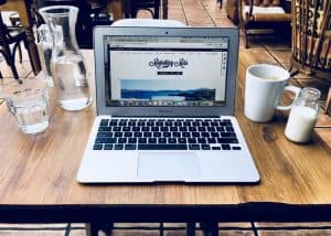 Laptop on table at cafe with coffee and water - Blog Post Writing Tips