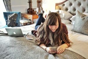How to Find your Blogging Niche - Lying on hotel bed with phone and laptop working