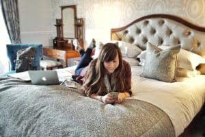Social Media Tips for Bloggers - Lying on hotel bed working on phone with laptop