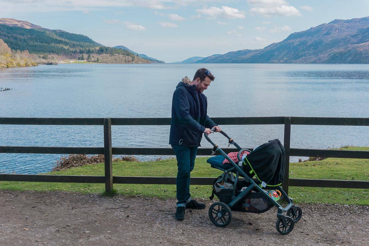 Man with pram in front of lake and mountains in Scotland