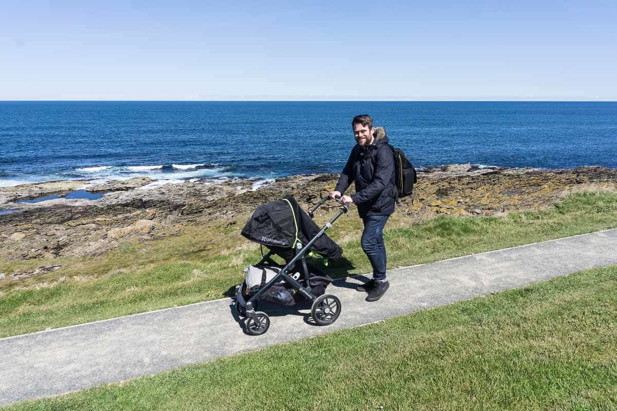 Pushing pram along path by the sea