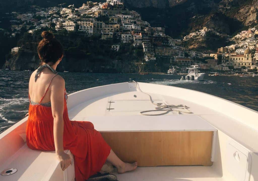 Babymoon Destinations Europe - Amalfi Coast - On boat in red dress looking at coastal village. 