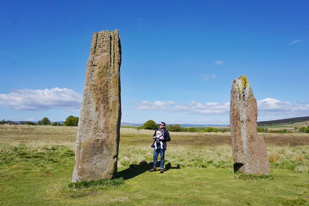 Standing stones in field and man with baby