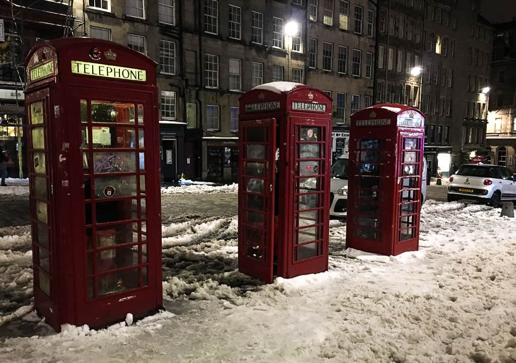 Royal Mile in Edinburgh in Winter with snow and red phone boxes