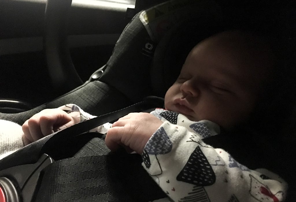 Baby asleep in car seat on road trip with baby