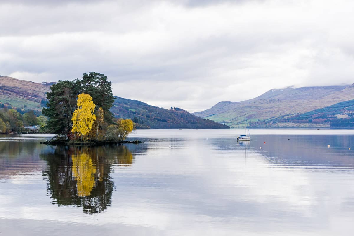 Calm lake with island with multicoloured autumn trees, Loch Tay Perthshire Scotland