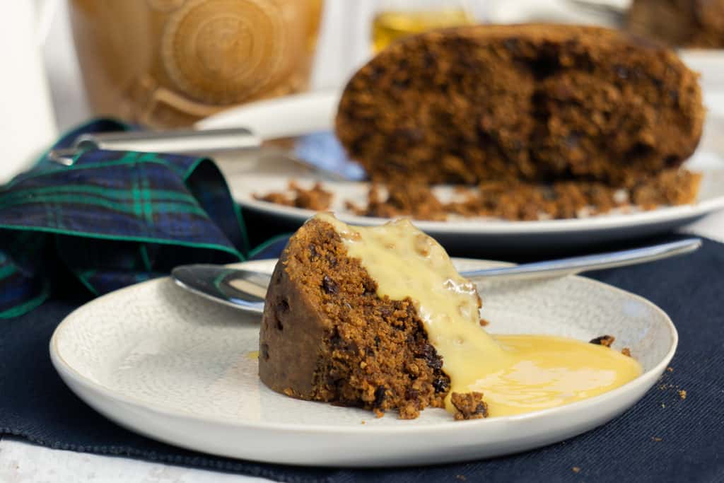 Clootie Dumpling on a plate with custard for Christmas